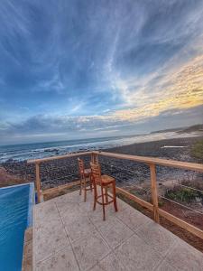 two chairs sitting on a balcony overlooking the beach at Oceanfront Villa, Punta Mango in Jucuarán