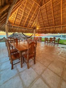 a dining room with a table and chairs under a straw roof at Oceanfront Villa, Punta Mango in Jucuarán +16 photos