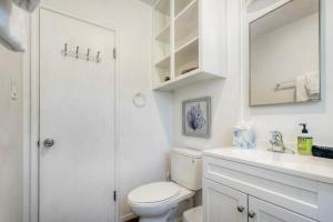 a white bathroom with a toilet and a sink at Oceanfront unit, Private Balcony, Beach Access, Sunset Views in Carlsbad +36 photos