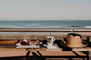 a table with a hat and a cup of coffee and a cake at Baya Hotel in Capbreton