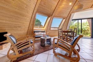 a log cabin living room with chairs and a couch at Les Dômes Du Ponant in Plouguerneau