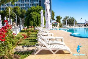 a row of white lounge chairs next to a swimming pool at Hotel Carmen Tower - Balada in Saturn