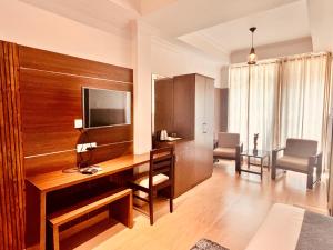 a room with a desk with a television and chairs at Matha Residency in Kasauli