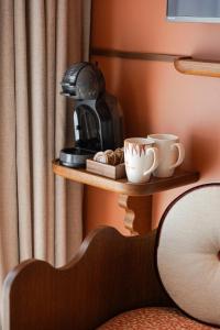 a coffee maker on a shelf with cups on it at Posidonia Hôtel in Nice
