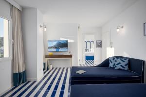 a living room with a blue couch and a tv at Villa Lia Hotel Capri in Capri