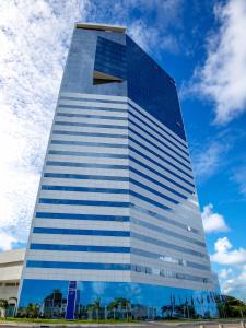 a tall glass building with a blue sky in the background at Bugan Premium 16 andar - vista mar incrível in Recife
