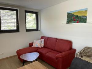 a living room with a red couch and two windows at Apartment Turmfalke in Vogtsburg