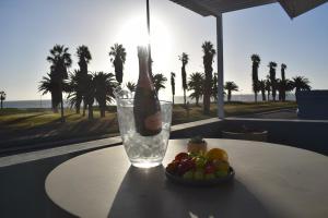 a bottle of champagne sitting on a table with a bowl of fruit at La Flamingo Guesthouse in Walvis Bay