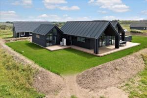 a house with a black roof on a grass field at LN1842-Hjorring-Lobet-5 in Hjørring