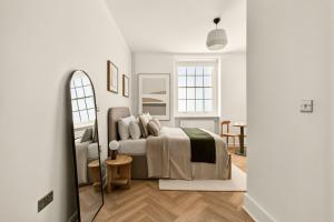 a white bedroom with a bed and a table at GuestReady - The Crescent in London