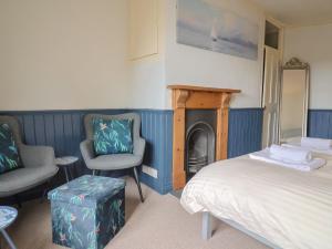 a bedroom with a bed and two chairs and a fireplace at 5B Bridge Street in Lyme Regis