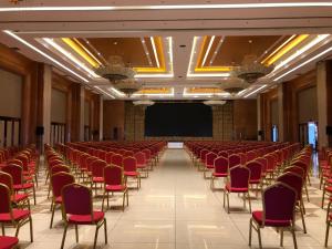 an empty hall with red chairs and a projection screen at Gloria Hotel in Polana Caniço "A"