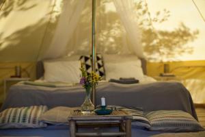 a bed with a table with a vase of flowers on it at Glamping - a living room overlooking the ocean in Hammarland