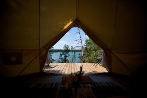 a tent with a view of a lake in the background at Glamping - a living room overlooking the ocean in Hammarland