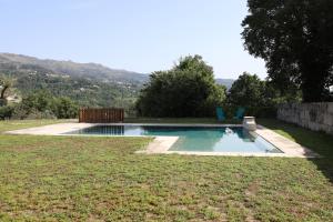 a swimming pool with two blue chairs in a yard at Retiro Maria Idalina in Amarante
