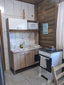a small kitchen with a stove and a microwave at Chalés Lar Doce Mar in Jaguaruna