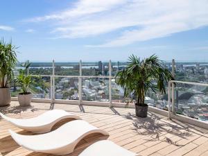 a balcony with two white chairs and palm trees at Mercure Rosario in Rosario