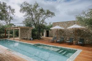 a pool with chairs and umbrellas next to a building at Saseka Tented Camp in Hoedspruit +37 photos