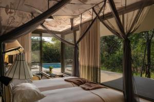 a bedroom with three beds and a large window at Saseka Tented Camp in Hoedspruit