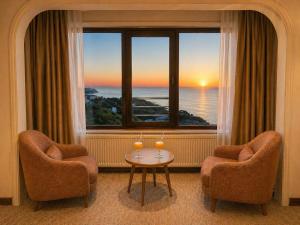 a room with two chairs and a table in front of a window at EMİRGAN Otel in Bağlık