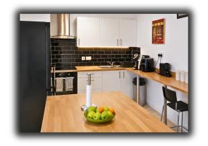 a kitchen with a bowl of fruit on a wooden table at Kop View Rooms in Liverpool