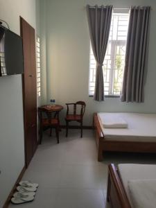 a room with two beds and a table and a window at Khách Sạn Đào Nguyên in Tuy Phong