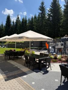a patio with tables and chairs under an umbrella at Hotel Jakuszyce Sport & Spa in Szklarska Poręba