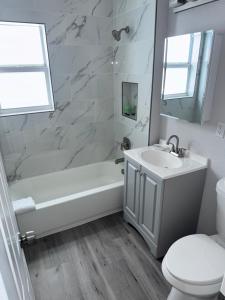 a bathroom with a tub and a sink and a toilet at The Tel Ft Lauderdale in Fort Lauderdale