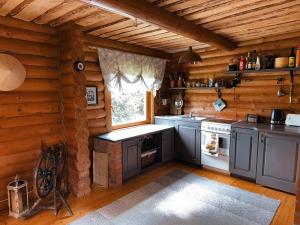 a kitchen in a log cabin with a stove and a window at Hubane palkmaja Otepää südames in Otepää