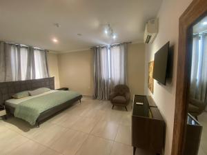 a bedroom with a bed and a television and a chair at Casa Bianca in Accra