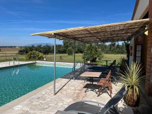a patio with a picnic table and a roof over a pool at B&B El Ranxo in Franciach