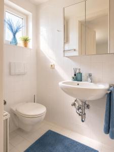 a white bathroom with a sink and a toilet at Seeparadies in Unter Feuchten +10 photos