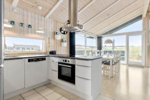 a kitchen with white appliances and a dining room with a table at LN1954-Hirtshals-Harestien-27 in Hirtshals