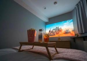 a table on top of a bed with a movie on the wall at Doux Pavillon - Sauna - Jacuzzi in Tassin-la-Demi-Lune