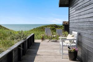 two chairs and a table on a wooden walkway to the ocean at LN1938-Hirtshals-Kranken-9 in Hirtshals