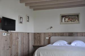 a bedroom with a bed with a tv on the wall at B&B Knotwilgenhoeve in Knokke-Heist