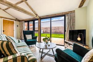 a living room with couches and a tv and a table at Shippon 1 in Radley