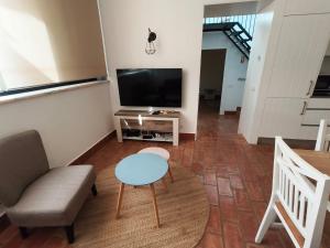 a living room with a tv and a chair and a table at Deluxe 2 Terraces River&Marina View Flat in Ferragudo