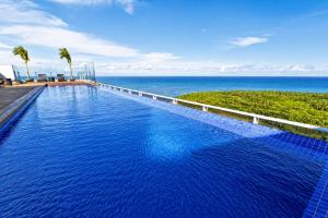 a large swimming pool with a view of the ocean at Bugan Premium 16 andar - vista mar incrível in Recife