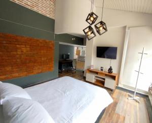 a bedroom with a large white bed and a tv at Textileria in Pereira