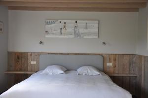 a bedroom with a white bed with a picture above it at B&B Knotwilgenhoeve in Knokke-Heist