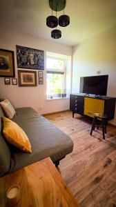 a living room with a couch and a flat screen tv at Apartament Antracytowe Wrota 3 in Boguszów-Gorce