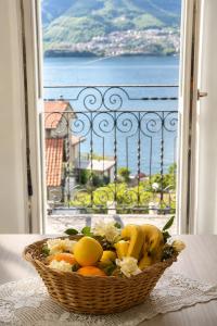 a basket of fruit on a table in front of a window at Lescen White Residence - Lake View in Lezzeno