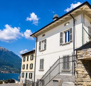 a white building with a fence next to a lake at Lescen White Residence - Lake View in Lezzeno