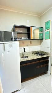 a kitchen with a sink and a refrigerator at Loft Charmoso Privativo in Volta Redonda
