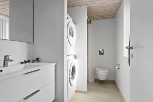 a white bathroom with a washing machine and a sink at LN1865-Hirtshals-Krageklit-30 in Hirtshals +29 photos