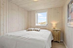 a bedroom with a white bed with a window at LN1865-Hirtshals-Krageklit-30 in Hirtshals