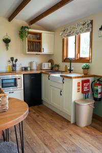 a kitchen with white cabinets and a wooden floor at Lintmill Lodges - Heather Shepherds Hut in Sorn +5 photos