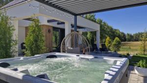 a hot tub in a backyard with a pergola at Bosarosa Forest & Lake Villa z jacuzzi wanna SPA in Laski Małe