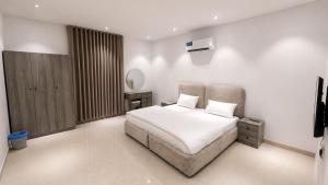 a white bedroom with a bed and a mirror at أرياف سويت in Al Baha